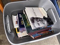 Bin containing stack of hardcover and softcover books, top book The Cinema of George Lucas visible