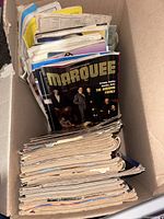 Box containing stack of assorted magazines, Marquee visible
