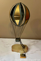 Full view of metal hot air balloon sculpture on stone base with tag visible