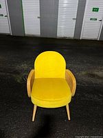 Front view of yellow accent chair showing upholstery, curved back, wood frame, tapered legs