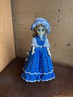 Full view of doll standing in crocheted dress and bonnet