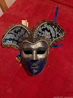 Front view of full-face blue and gold jester mask with brocade headdress