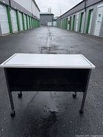 Front view of rolling utility table showing open shelf and casters