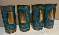 Front view of four teal and gold highball glasses