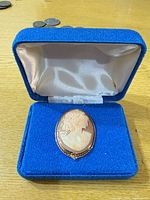 Cameo brooch displayed in open blue box