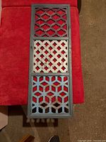 Full view of three-panel lattice wood panel on red background