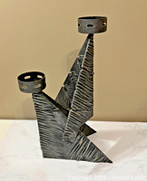 Full view of brutalist metal candelabra showing two candle cups and overall shape