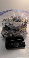 Full Ziploc bag of assorted jewelry on digital scale