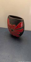 Front view of black vase with red floral design