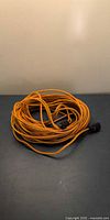 Coiled orange extension cord showing full length and connectors