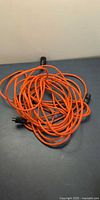 Coiled long orange extension cord with black ends