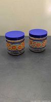 Front view of both glass jars showing orange slice graphics and blue lids