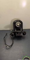 Front view of black rotary wall telephone with handset attached