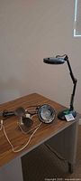 Desk showing assembled black magnifying lamp and separate lamp parts