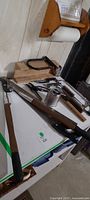 Overview of loppers, saw, pruners, wire brush, coil of wire and accessories on table