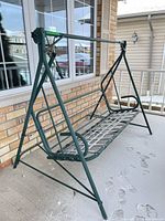 Full view of green steel porch swing frame on porch