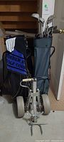 Overall lot showing two golf bags with clubs, towel, glove, and folded cart