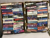 Two boxes filled with approximately 60 paperback novels, stacked tightly. Books vary in spine color and author, titles visible include Sherrilyn Kenyon, Heather Graham, Charlotte MacLeod, Judith Arnold, Diana Palmer, Julie Garwood, and others.