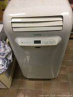 Front view of the white upright air conditioner unit showing the adjustable air vent and digital control panel.