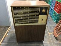 Front view of Air King dehumidifier showing wood panel cabinet, large front grille and control knob with power light.