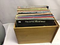 Wooden crate filled with approximately 50 LP records with mixed condition visible, featuring 'This Is The Moody Blues' album on top.