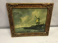 Front view of vintage windmill print in decorative antique frame with visible wear and damage.