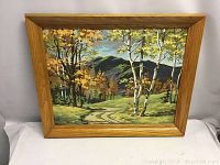 Full view of the framed oil painting showing the fall landscape including trees, path, and mountains.