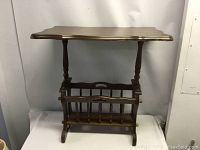 Full view of the wooden occasional table with magazine rack, showing scalloped top, turned legs, and magazine rack with spindle dividers.