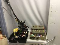 Multiple fishing rods with reels, two tackle boxes with compartments open showing assorted fishing tackle including lures and fishing line.