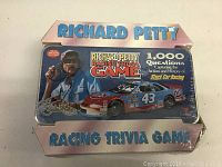 Photo of front of vintage Richard Petty Racing Trivia Game metal tin, showing unopened and sealed packaging with graphics of Richard Petty and his car.