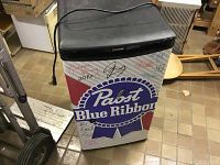 Frontal photo of mini fridge with Pabst Blue Ribbon logo and several signatures on the door, black top control panel with Danby branding.