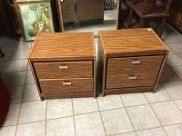 Two matching wood night stands with two drawers each, placed side by side on tile floor.