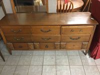 Full front view of wooden dresser showing top surface, nine drawers, brass handles, and carved lower panels.