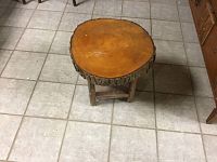 Full view of the tree stump stool showing the top surface and legs, placed on tile floor.