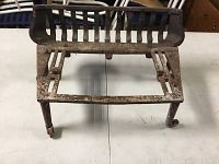 Top view of antique cast iron fireplace insert showing open grate and four legs.