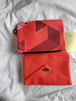 Front view of both red pouches showing geometric Tetris design and envelope style with wing emblem