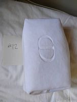 Side view showing embossed CD logo on white makeup bag