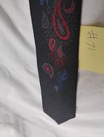 Front section of black tie showing red and blue abstract woven pattern