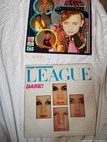 Both record sleeves laying side by side on surface