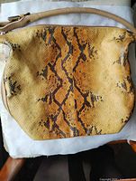 Front view of tan and brown faux snakeskin handbag