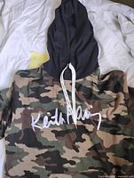 Full view of camouflage short-sleeve hoodie with black hood and Keith Haring logo
