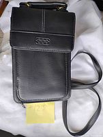 Front view of black leather crossbody organizer bag with flap closed