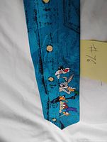 Full view of blue tie showing characters and button graphics