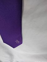 Front of purple skinny tie showing embroidered penguin logo
