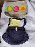 Overview of both the navy clutch and beige L’Occitane makeup bag
