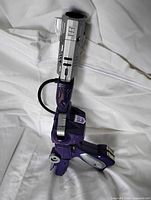 Full view of purple and silver Shockwave figure in gun mode on white cloth