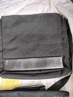 Front of Tumi messenger bag showing leather logo trim and flap
