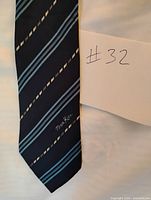 Full view of navy tie showing stripe pattern and Nina Ricci logo