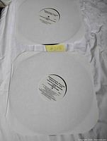 Both vinyl records in white paper sleeves showing centre labels