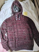 Full view of maroon cable knit hooded sweater laid flat showing overall condition and design